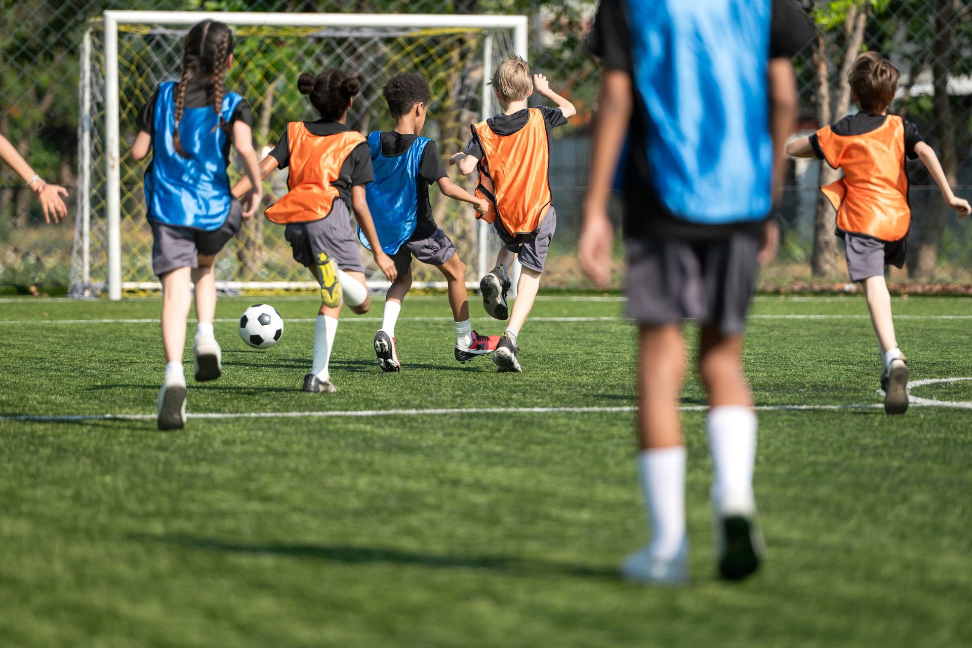 Group of international school kids playing soccer together on the field, showing teamwork, diversity, and active childhood lifestyle